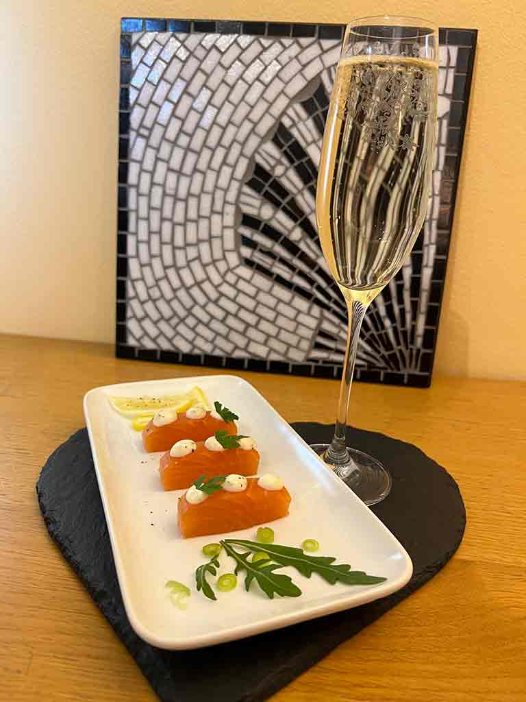 FOOD 2 A rectangular plate with delicate Balik salmon, topped with horseradish cream buttons, served with salad and champagne