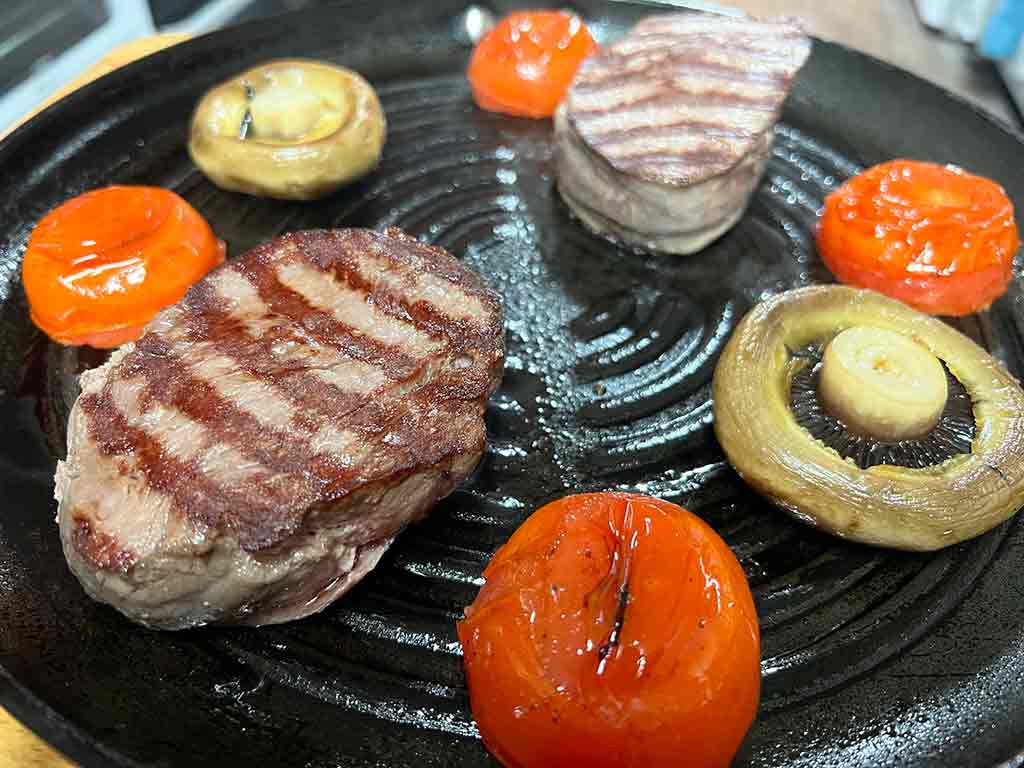 FOOD 7 A griddle sizzling fillet steaks, mushrooms and tomatoes
